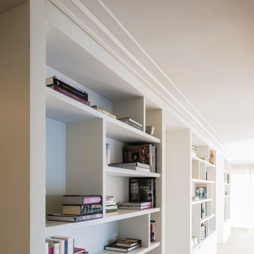 Modern flat crown molding; crown molding has an asymmetrical profile with an extended top surface projection across the ceiling